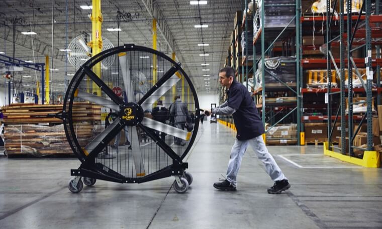 Big Ass Fans employee pushing a large directional fan in a warehouse