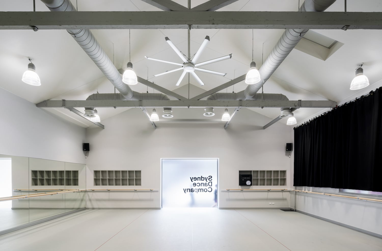 Large commercial white ceiling fan installed in a bright dance studio