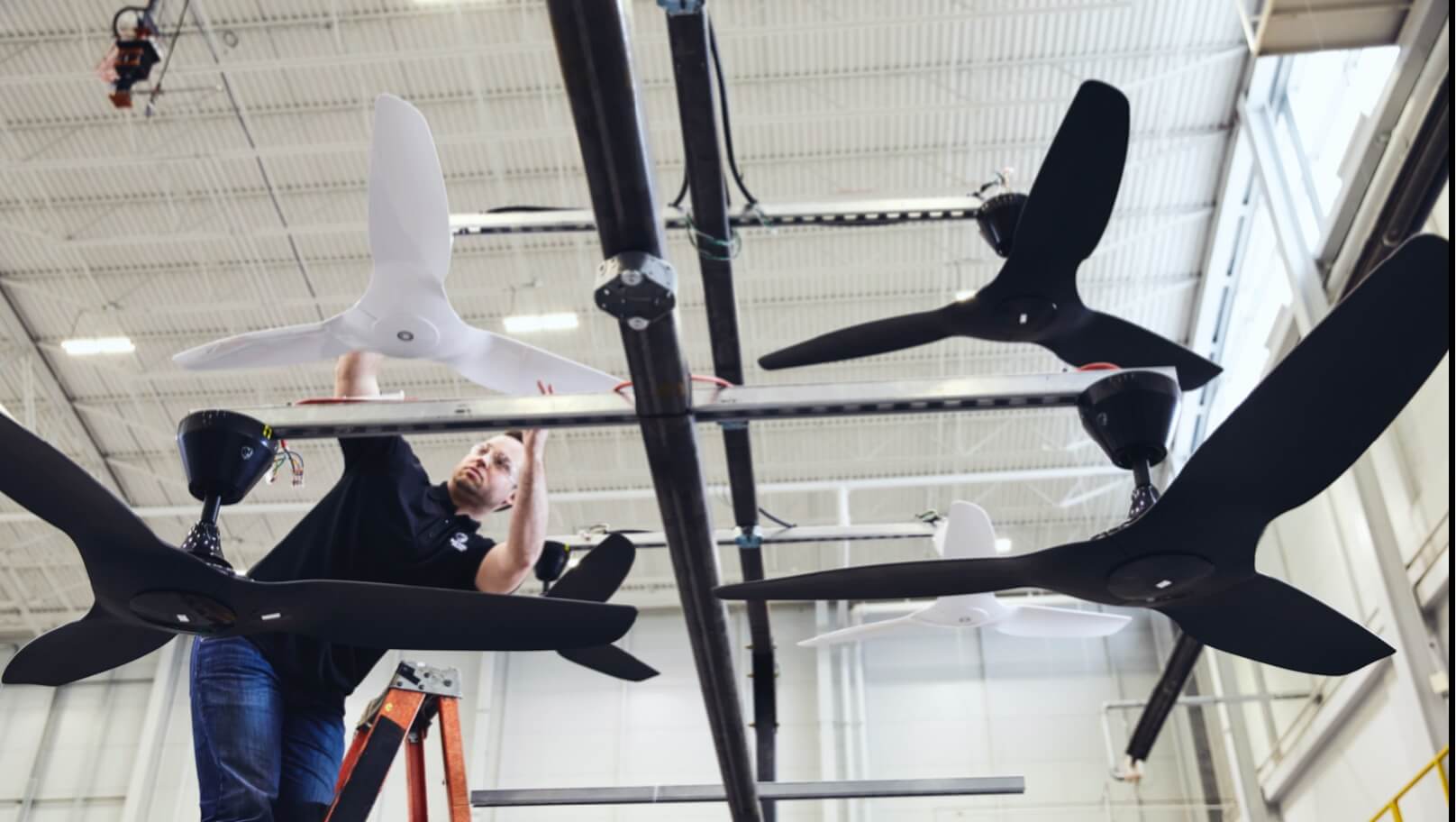 Big Ass Fans employee installing haiku fans while standing on a ladder