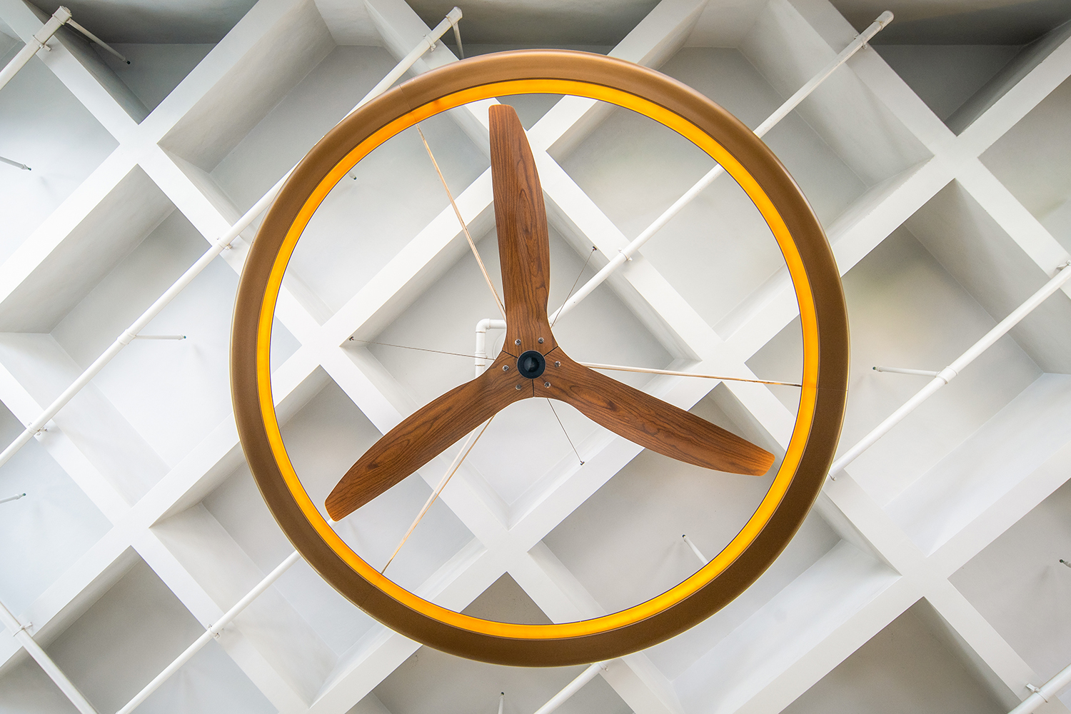 Close-up of a modern ceiling fan with wooden blades and a circular LED frame