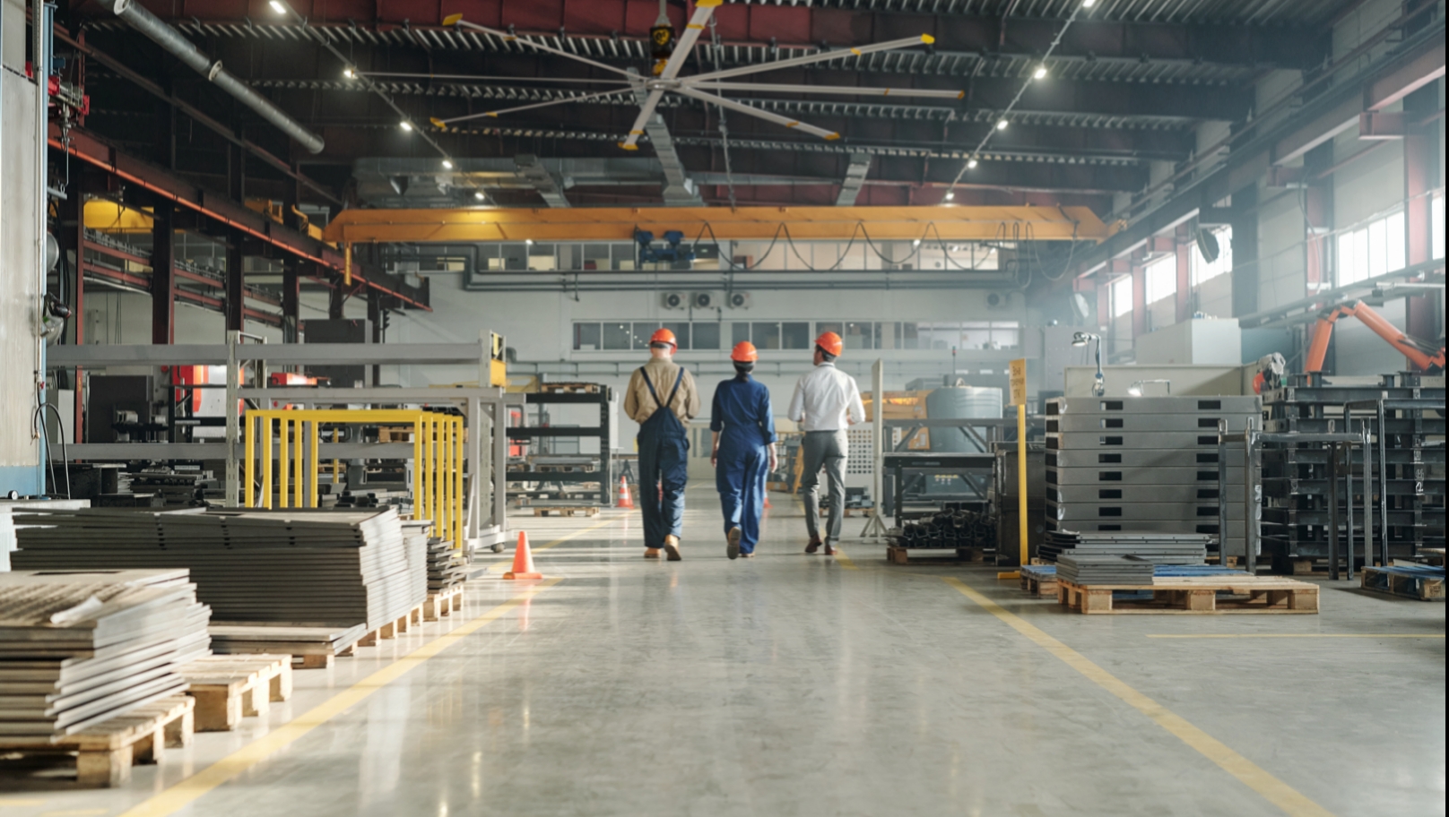 Big Ass Fans employees walking through a factory with a large industrial ceiling fan overhead